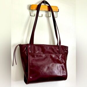 HOBO red shoulder bag in polished leather. Exterior sides pockets. Zip closure